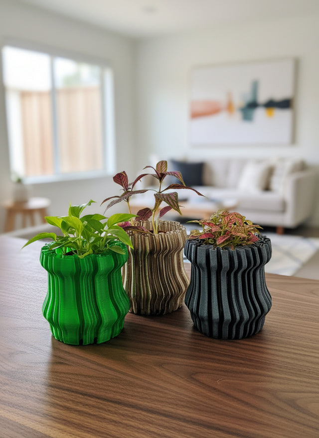 Three ribbed ceramic planters with plants on a wooden table in a living room.